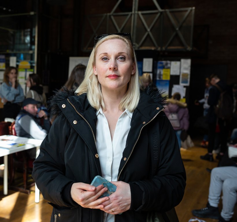 Lisa Bjurwald i ytterkläder i en lokal med människor i bakgrunden